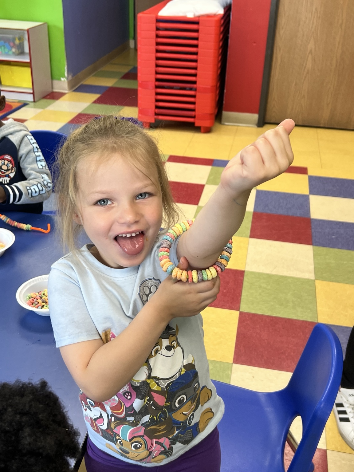 A child proudly showing a colorful bracelet she created at Building Blocks
